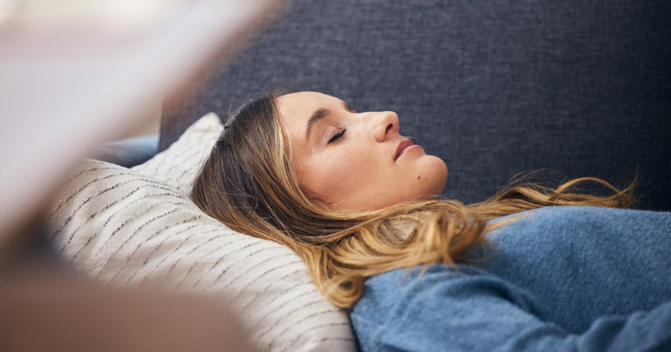 Woman lying on couch with eyes closed.